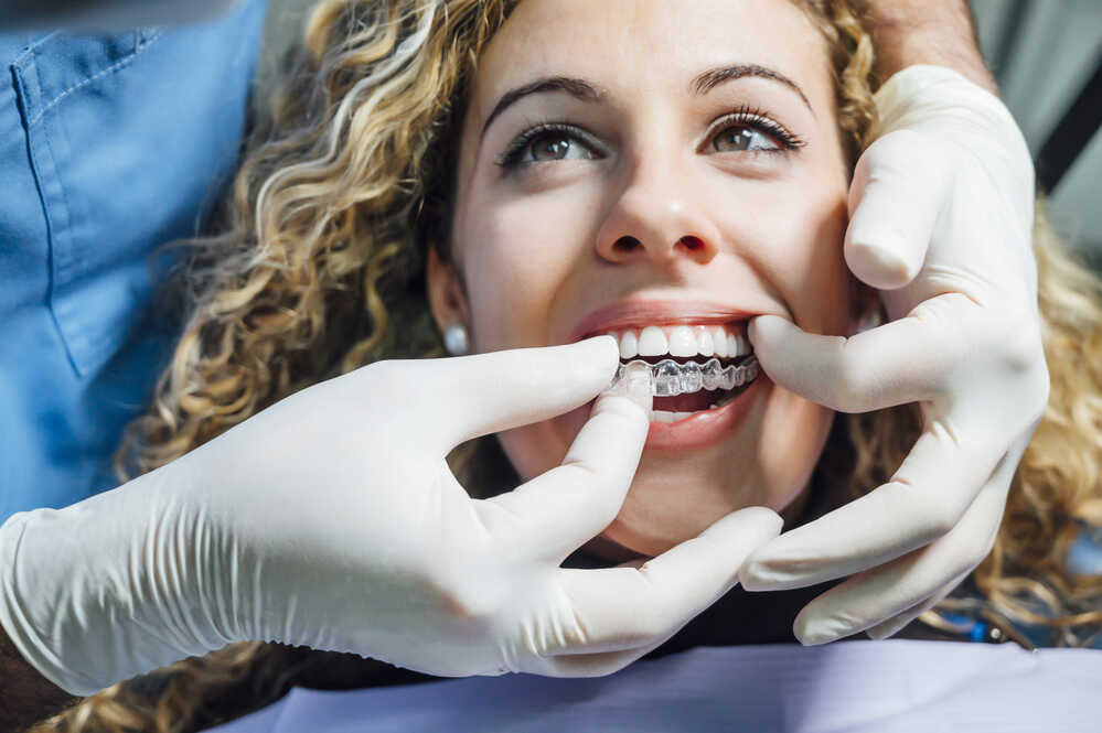 ortodonta nakłada pacjentce aparat invisalign na zęby